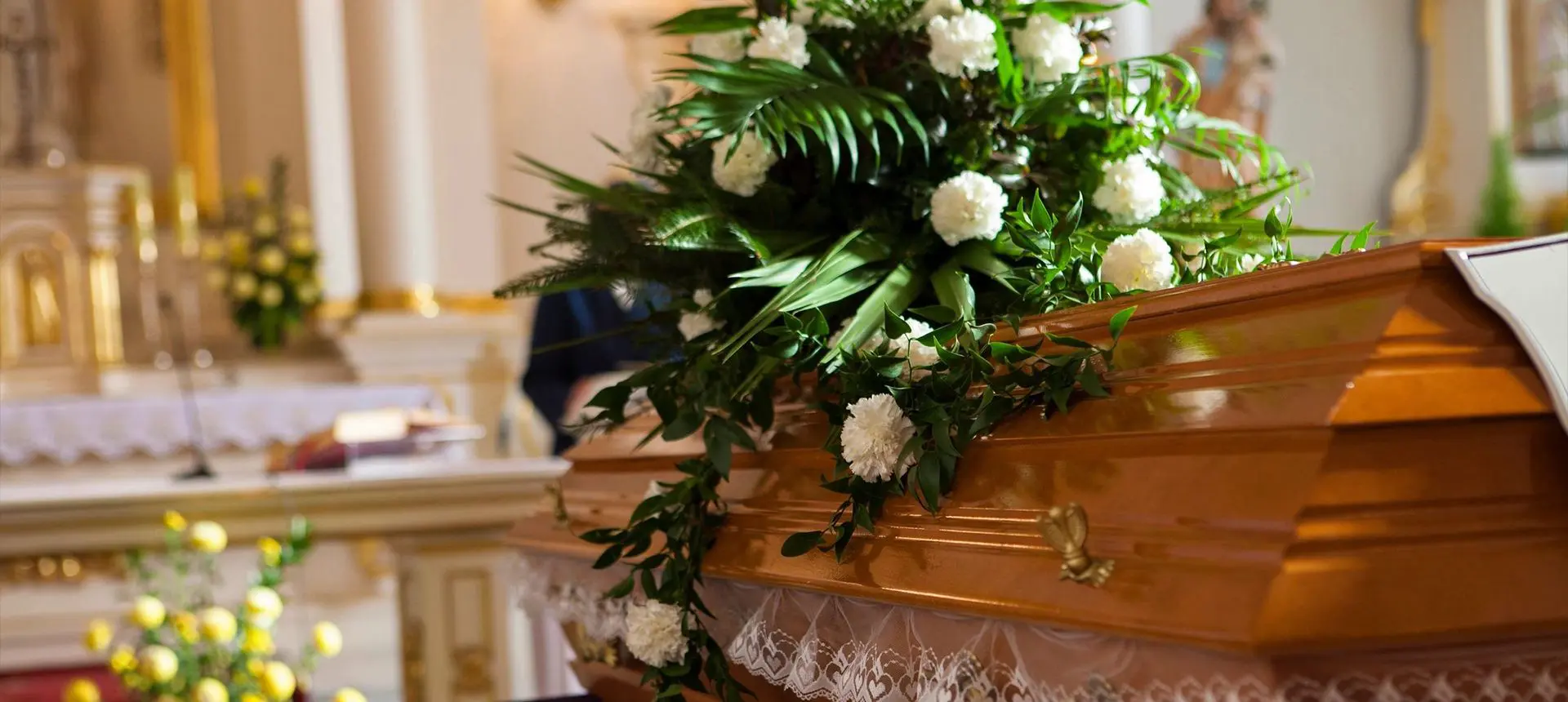 A wooden casket with flowers on top of it.