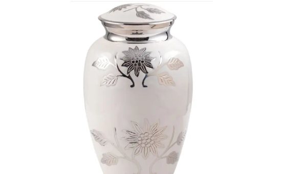 A white and silver urn with flowers on it.